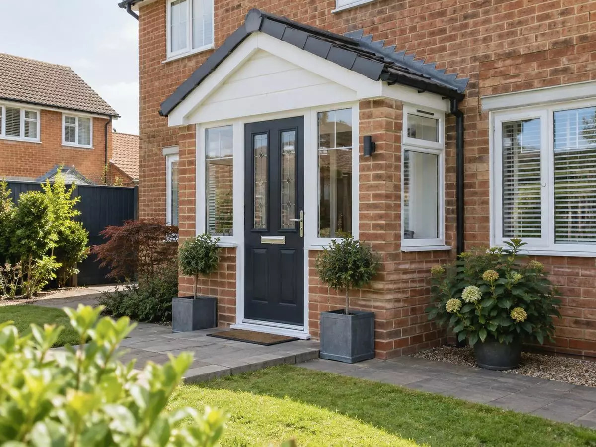 Enclosed brick porch with a pitched roof, glazed side panels and a dark front door.