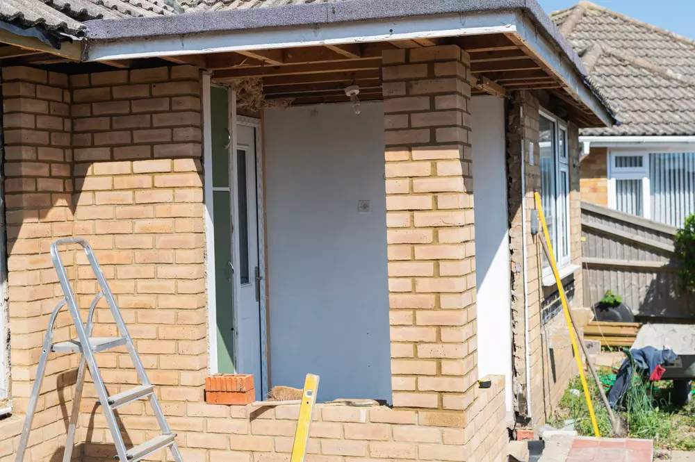 Bricklaying wall in an unfinished front porch renovation project