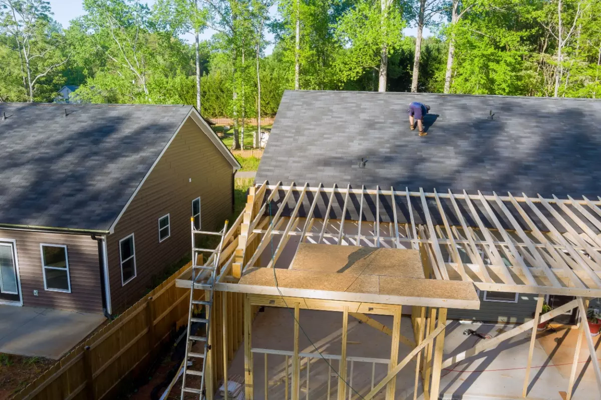 A roofer on top of a house installing a new roof.